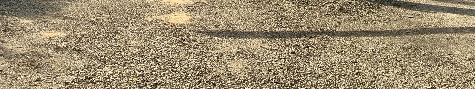 Verdichteter Schotter der Fahrgassen und Parzellen, dazwischen Holzstämme