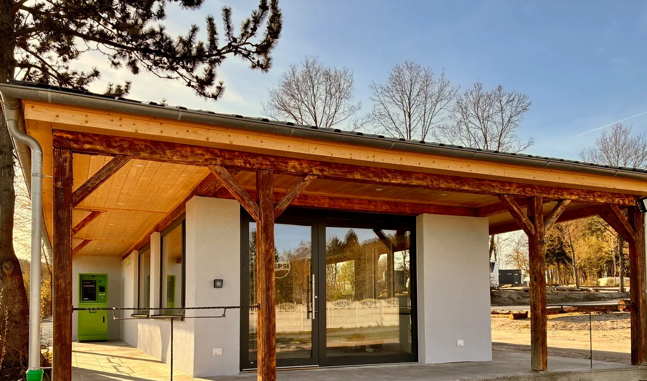 Der Kiosk am Platzeingang mit Holz-Vordach und Glasfront