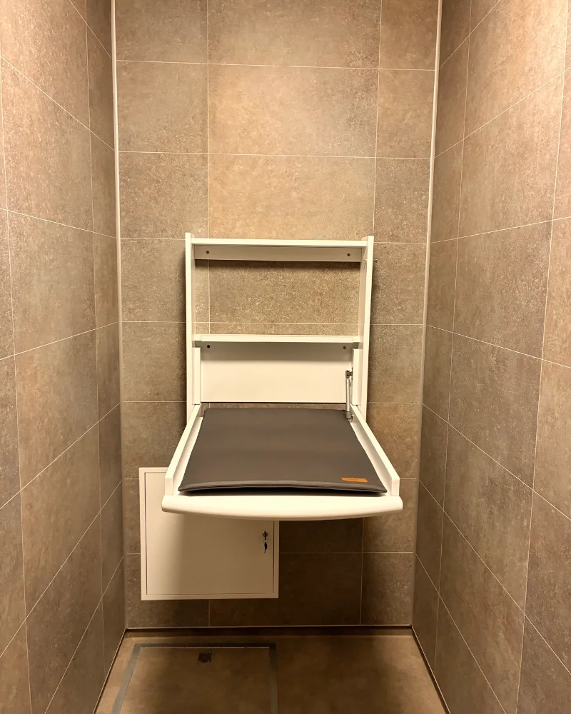 Fold-down baby changing table in a tiled cubicle